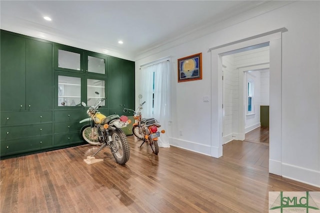 recreation room with baseboards, ornamental molding, wood finished floors, and recessed lighting