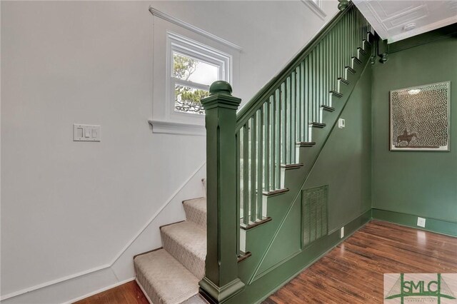 staircase featuring visible vents, baseboards, and wood finished floors