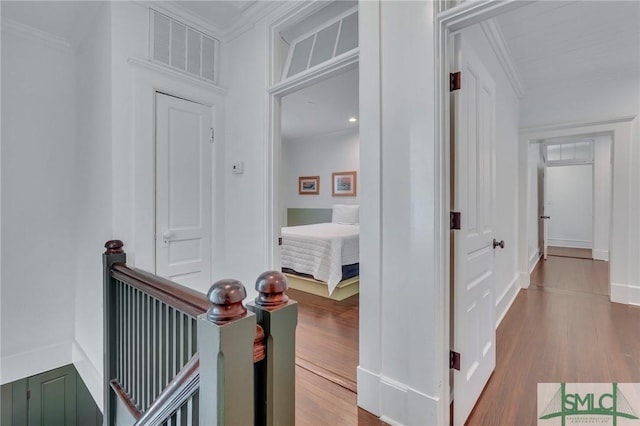 hall featuring ornamental molding, wood finished floors, visible vents, and baseboards
