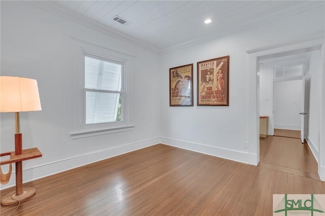 unfurnished room with baseboards, wood finished floors, visible vents, and crown molding