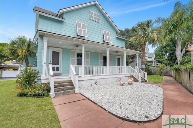 view of front of home featuring covered porch, fence, and a front yard