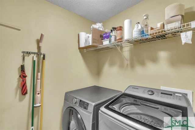 washroom featuring laundry area, a textured ceiling, and washer and dryer