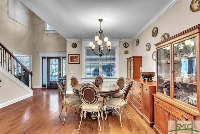 dining area featuring a notable chandelier, baseboards, ornamental molding, stairway, and light wood-type flooring