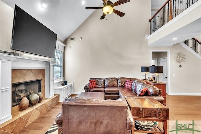 living room with baseboards, ceiling fan, a premium fireplace, wood finished floors, and stairs