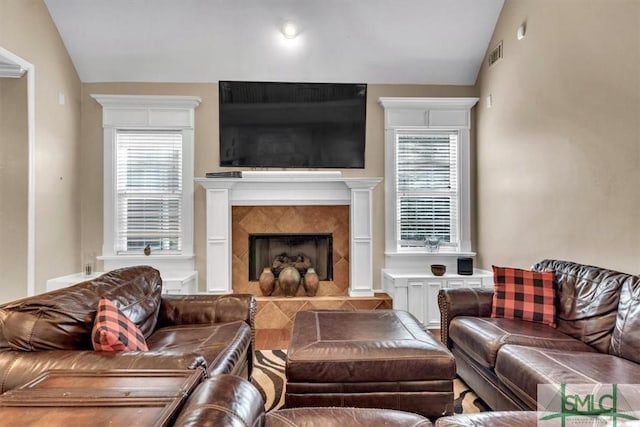 living room featuring lofted ceiling, visible vents, and a fireplace