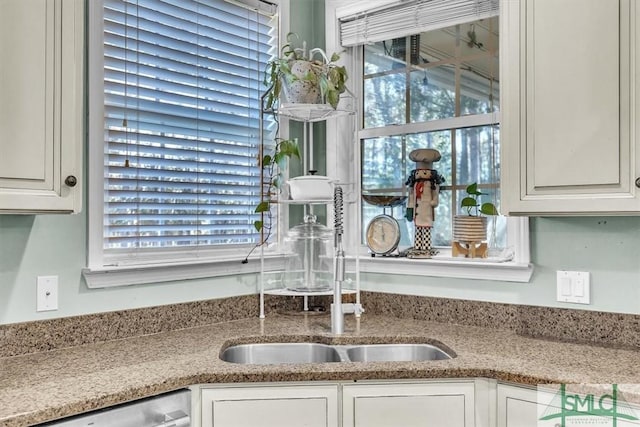 kitchen with white cabinets, dishwashing machine, and light stone countertops