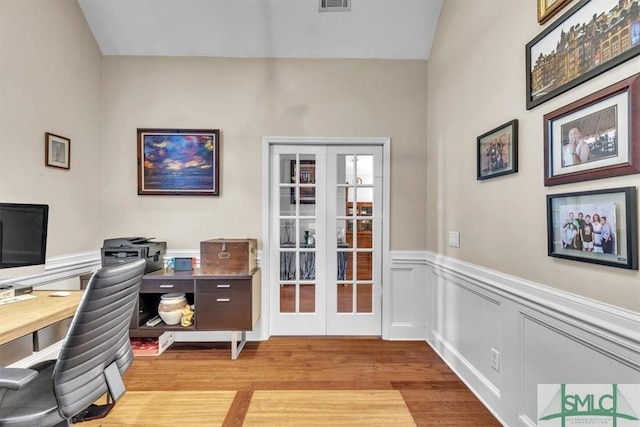 home office featuring light wood-style floors, french doors, a wainscoted wall, and visible vents