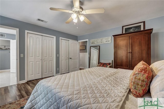 bedroom with a ceiling fan, visible vents, two closets, and wood finished floors