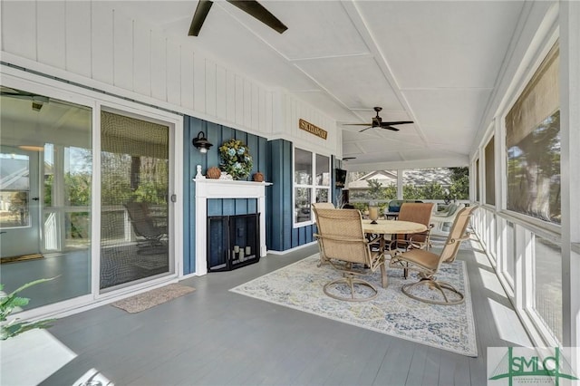 sunroom with ceiling fan, a tile fireplace, and lofted ceiling