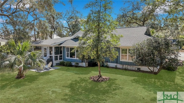 view of front of home featuring crawl space, roof with shingles, a front yard, and a sunroom