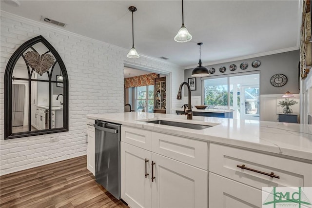 kitchen featuring brick wall, a sink, stainless steel dishwasher, and light stone countertops