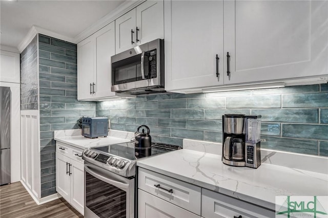 kitchen featuring appliances with stainless steel finishes, tasteful backsplash, white cabinets, and light stone countertops