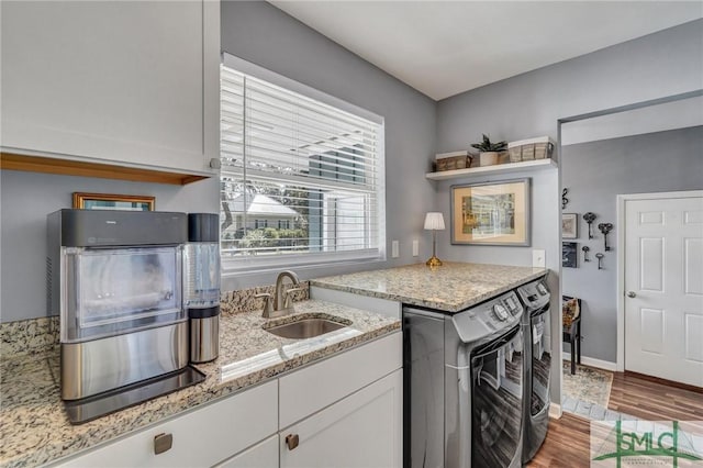 kitchen featuring wood finished floors, a sink, white cabinets, light stone countertops, and open shelves