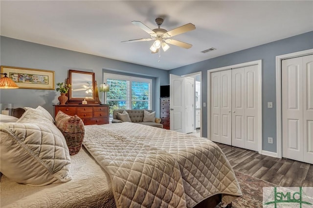 bedroom with ceiling fan, visible vents, baseboards, multiple closets, and dark wood-style floors