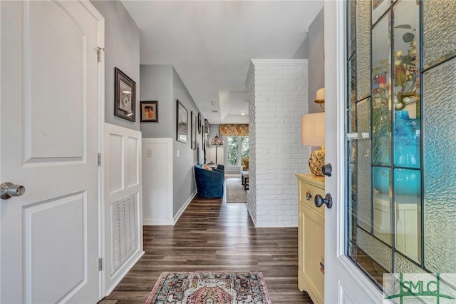 interior space with brick wall, dark wood finished floors, and baseboards