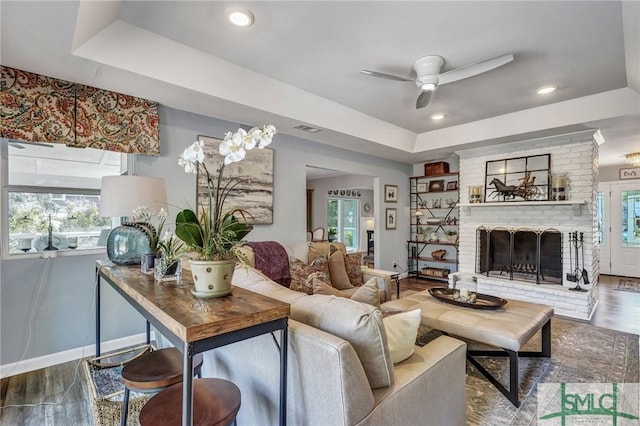 living room featuring a wealth of natural light, a raised ceiling, visible vents, and a fireplace