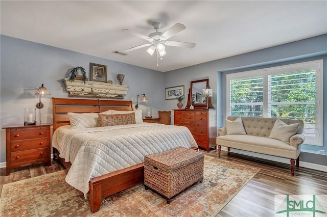 bedroom with ceiling fan, wood finished floors, visible vents, and baseboards