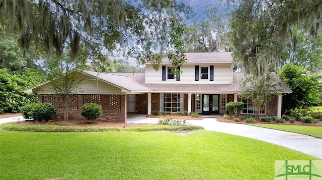 traditional-style home featuring french doors, brick siding, and a front lawn