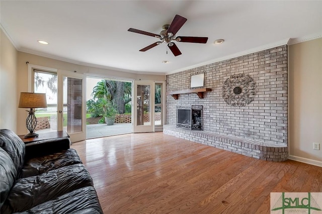 living area with plenty of natural light, a fireplace, wood finished floors, and crown molding