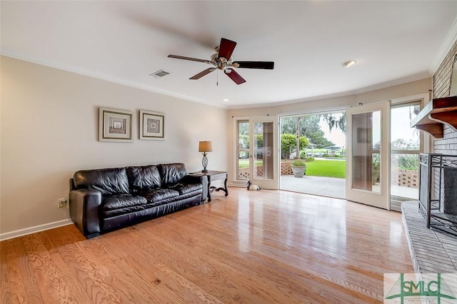 living area with baseboards, crown molding, visible vents, and wood finished floors