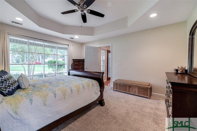 carpeted bedroom with a tray ceiling, recessed lighting, visible vents, ceiling fan, and baseboards