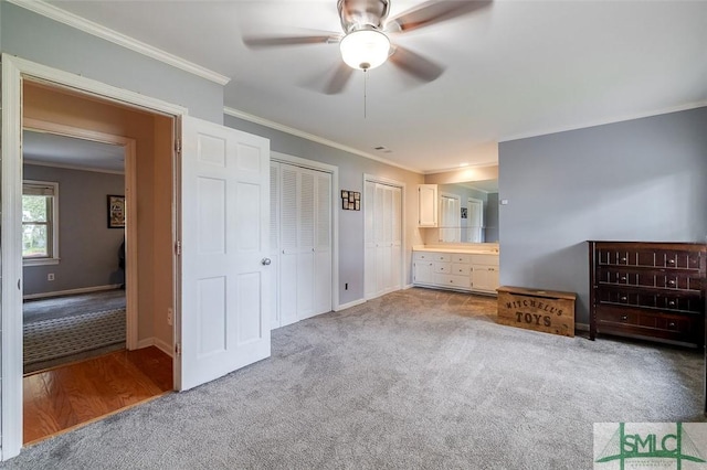 unfurnished bedroom featuring crown molding, carpet, baseboards, and multiple closets