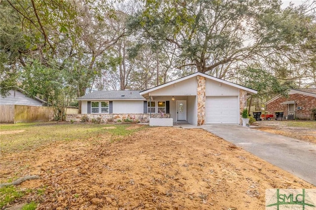 single story home featuring an attached garage, fence, stone siding, driveway, and a front lawn