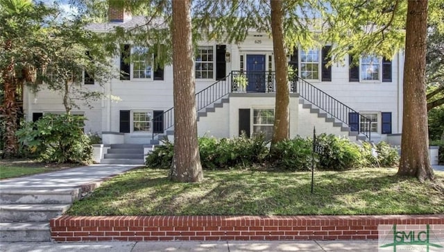 view of front facade featuring a front lawn, a chimney, and stairway