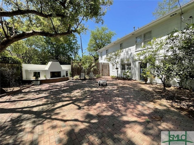 view of yard with an outdoor fireplace, fence, and a patio