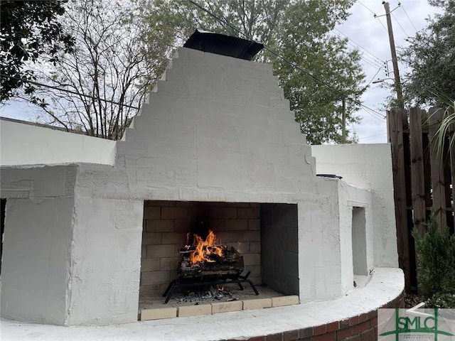 exterior details featuring fence and a lit fireplace