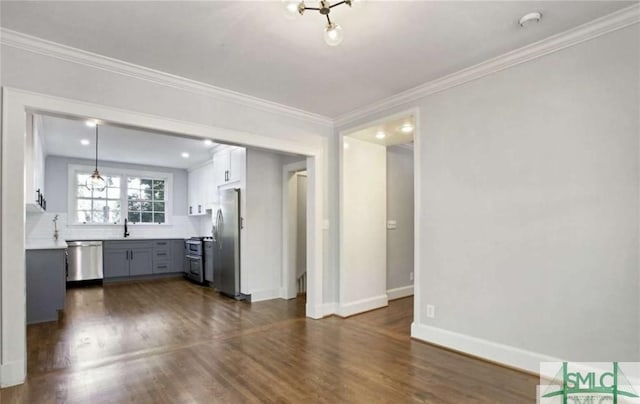 unfurnished living room with ornamental molding, a sink, dark wood finished floors, and baseboards