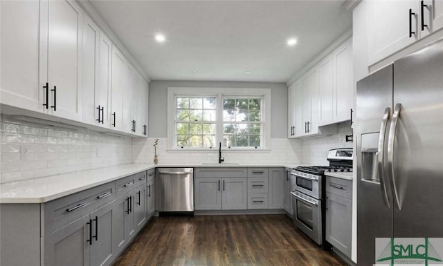 kitchen with dark wood-style floors, light countertops, stainless steel appliances, gray cabinetry, and a sink