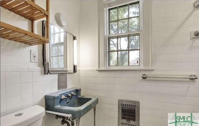 bathroom featuring toilet, a sink, tile walls, and heating unit