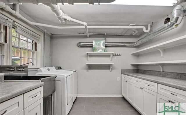 clothes washing area with baseboards, cabinet space, and washer and dryer