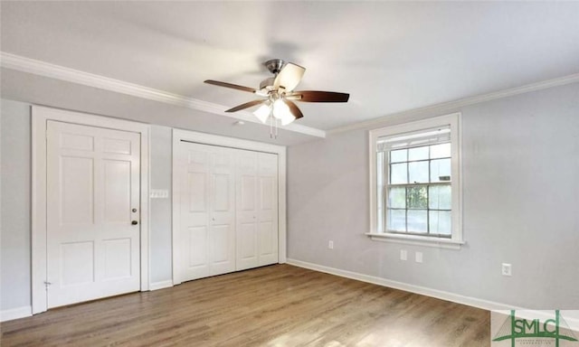 unfurnished bedroom featuring a ceiling fan, crown molding, baseboards, and wood finished floors