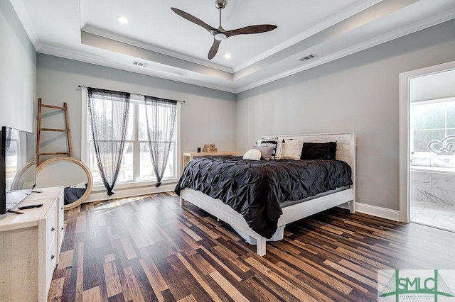 bedroom featuring wood finished floors, visible vents, baseboards, ornamental molding, and a raised ceiling