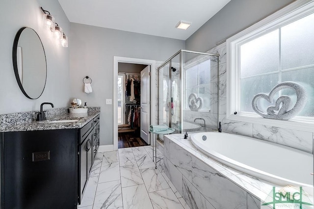 bathroom featuring marble finish floor, a spacious closet, vanity, a shower stall, and a bath