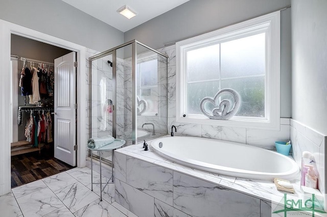 full bath featuring a garden tub, a walk in closet, and a shower stall