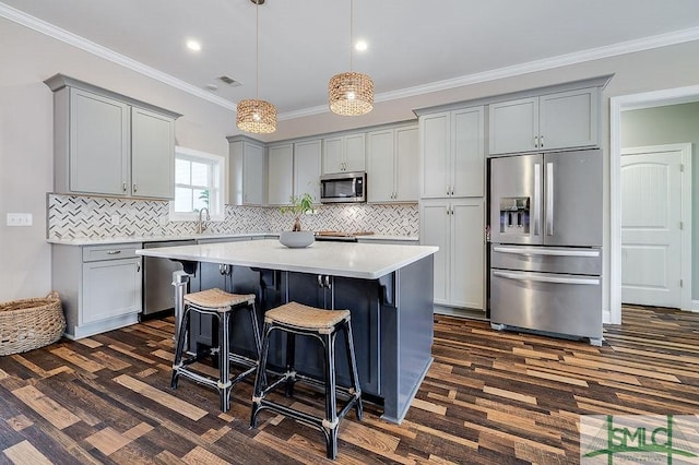 kitchen featuring stainless steel appliances, ornamental molding, a kitchen island, and gray cabinets