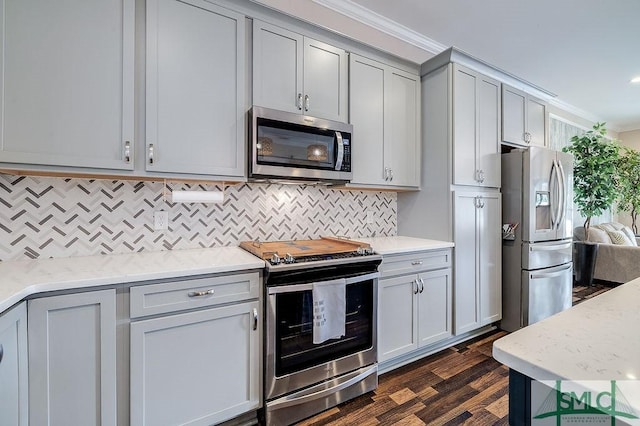 kitchen featuring tasteful backsplash, appliances with stainless steel finishes, dark wood-type flooring, and ornamental molding