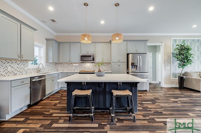 kitchen with crown molding, light countertops, gray cabinetry, appliances with stainless steel finishes, and a kitchen island