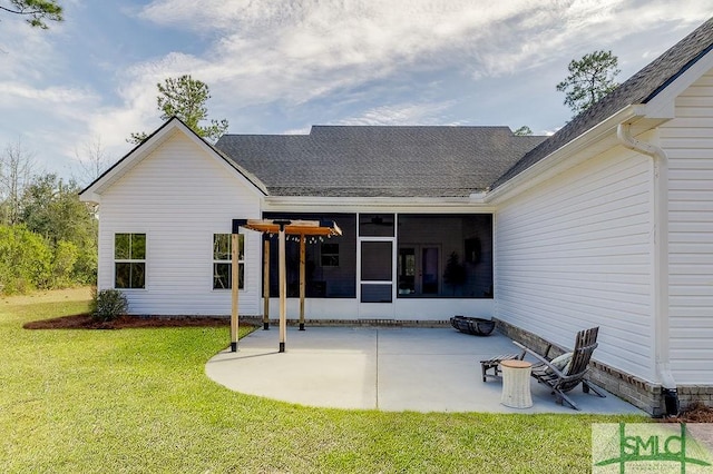 rear view of house with a patio area, a shingled roof, a lawn, and a sunroom