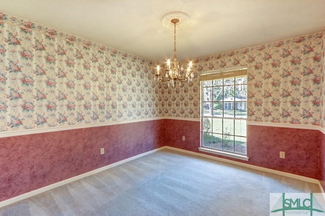 unfurnished room with a wainscoted wall, carpet flooring, a notable chandelier, and wallpapered walls