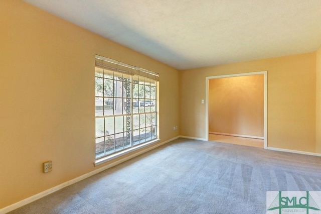 unfurnished room with carpet flooring and baseboards