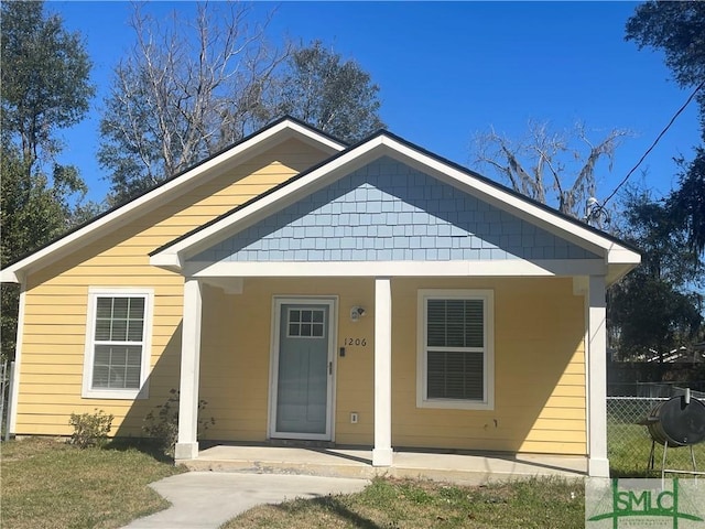 bungalow-style home with covered porch and fence