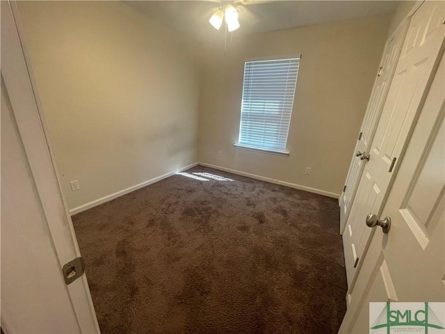 unfurnished bedroom with baseboards and dark carpet