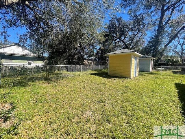 view of yard with a storage shed, a fenced backyard, and an outbuilding