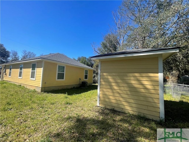 view of side of property with fence, an outbuilding, central AC, and a yard