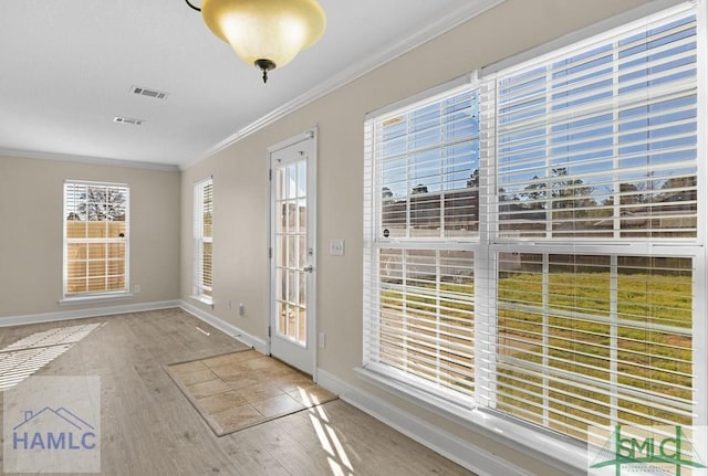 entryway featuring baseboards, visible vents, ornamental molding, and wood finished floors