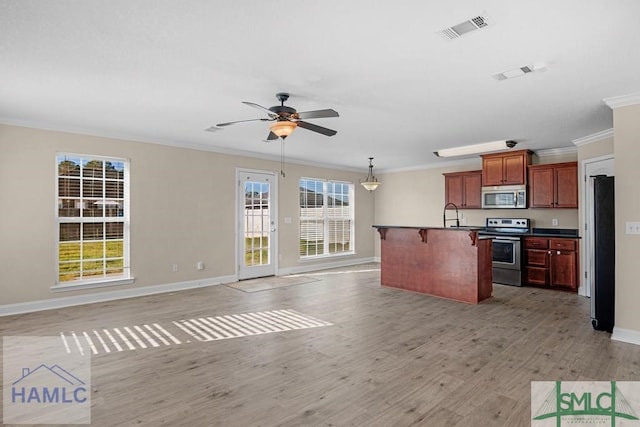 kitchen featuring appliances with stainless steel finishes, dark countertops, open floor plan, and visible vents